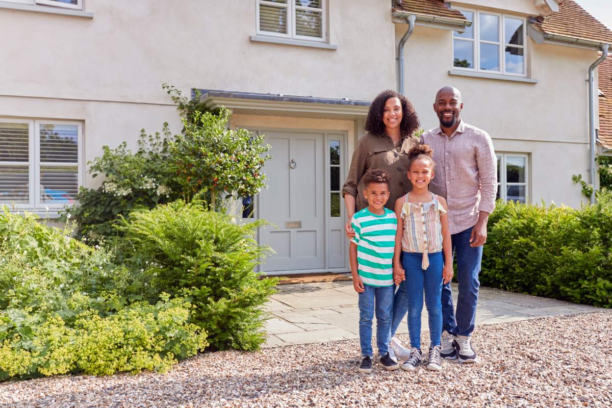 Portrait Of Smiling Family Standing Outside Home Together